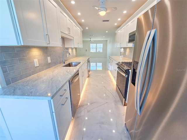 kitchen with sink, white cabinetry, ceiling fan, stainless steel appliances, and light stone countertops