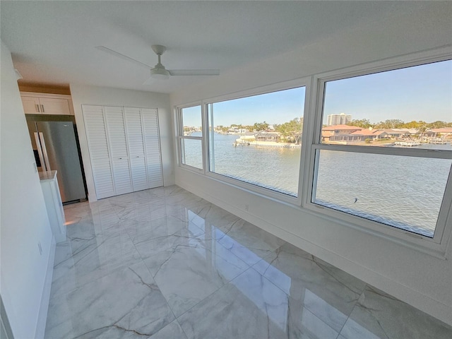 unfurnished bedroom with stainless steel fridge with ice dispenser, a closet, ceiling fan, and a water view