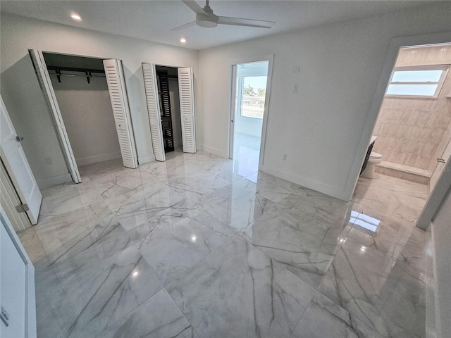 unfurnished bedroom featuring multiple windows, connected bathroom, two closets, and ceiling fan