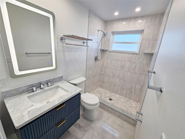 bathroom with vanity, tiled shower, and toilet