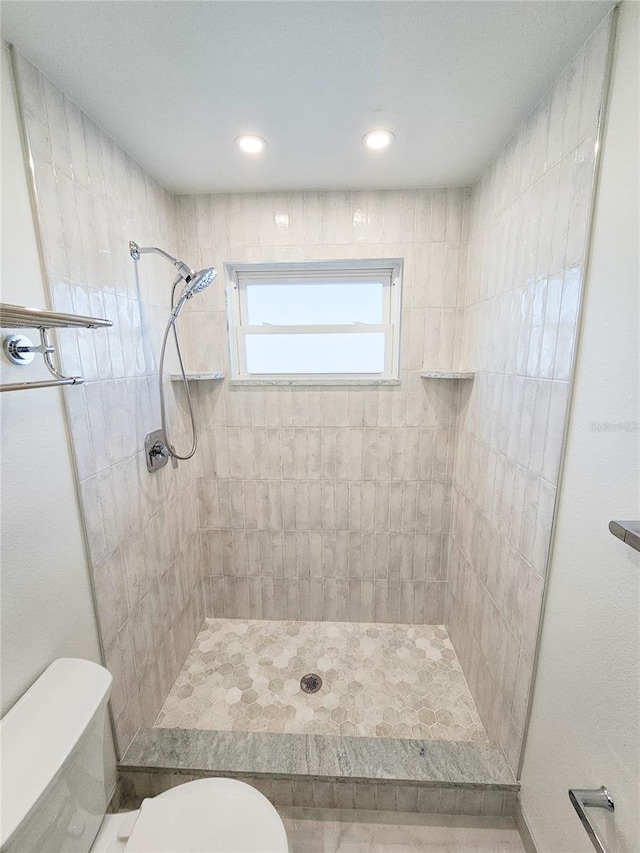 bathroom with tiled shower and toilet