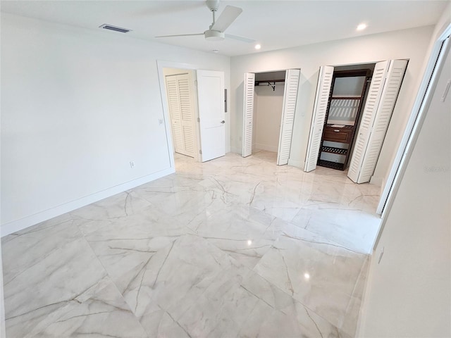 unfurnished bedroom with ceiling fan and two closets