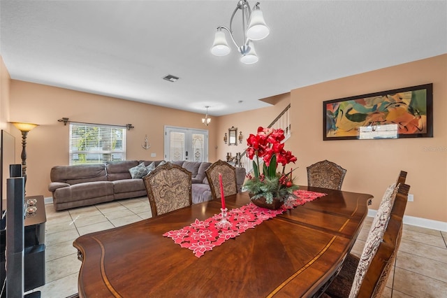 tiled dining space featuring a notable chandelier and french doors