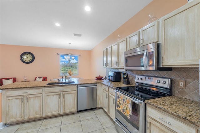 kitchen with kitchen peninsula, appliances with stainless steel finishes, sink, pendant lighting, and a chandelier