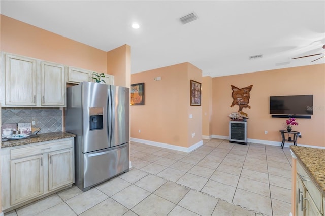 kitchen featuring decorative backsplash, stainless steel refrigerator with ice dispenser, light stone counters, cream cabinetry, and wine cooler