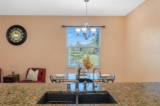 kitchen featuring a chandelier, pendant lighting, light stone countertops, and sink