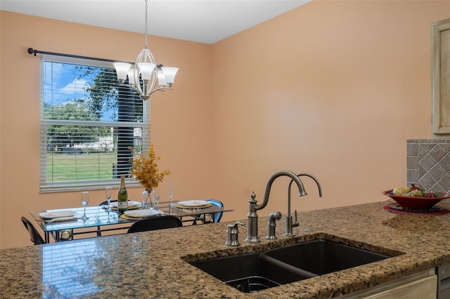 kitchen with a chandelier, stone counters, sink, and hanging light fixtures