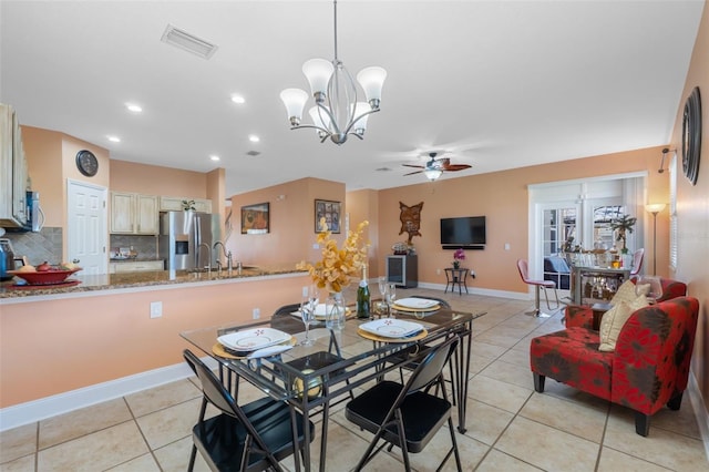 dining space featuring light tile patterned floors, ceiling fan with notable chandelier, and sink