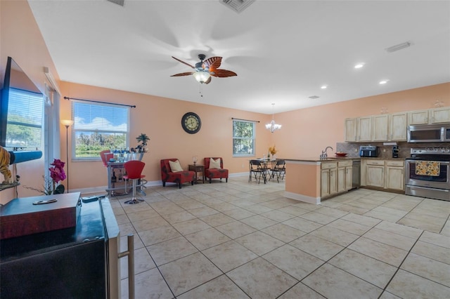 kitchen with ceiling fan with notable chandelier, stainless steel appliances, a wealth of natural light, and tasteful backsplash