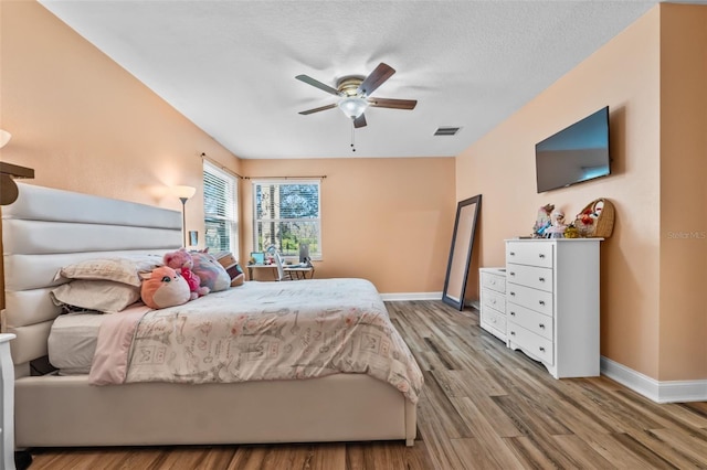 bedroom with ceiling fan, light hardwood / wood-style flooring, and a textured ceiling