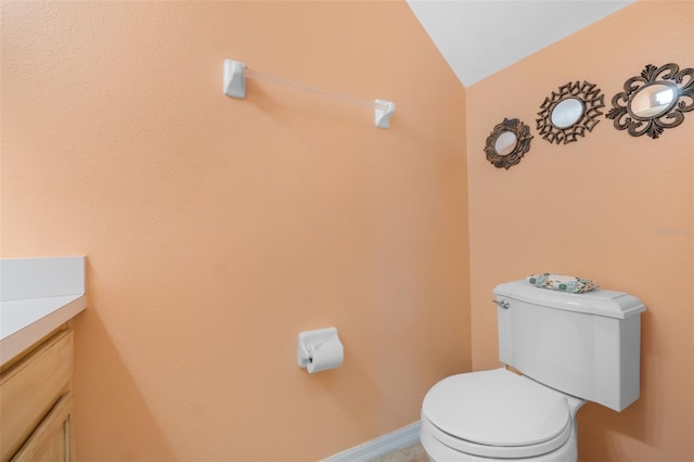 bathroom featuring toilet, vanity, and vaulted ceiling