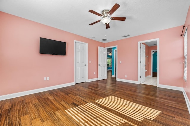 unfurnished bedroom featuring wood-type flooring, a textured ceiling, ensuite bath, and ceiling fan