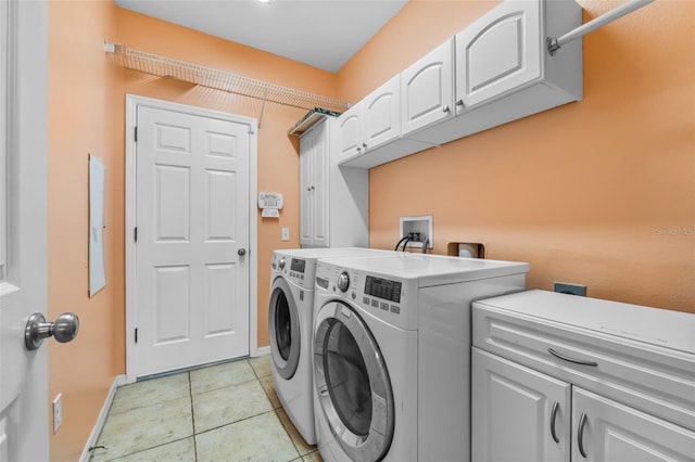 laundry area with cabinets, light tile patterned floors, and washing machine and clothes dryer