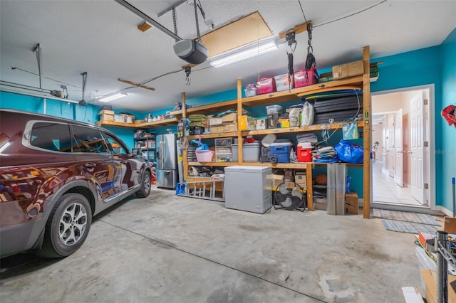 garage with a garage door opener, stainless steel refrigerator, and fridge