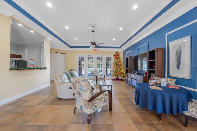 tiled living room with ceiling fan, crown molding, a tray ceiling, and french doors