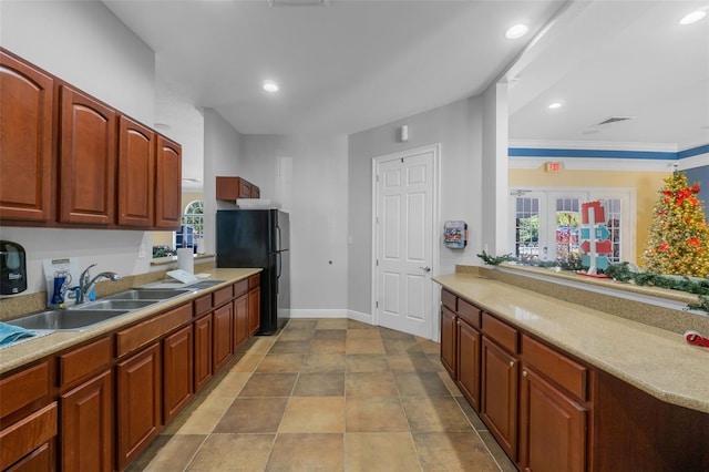 kitchen featuring crown molding, black refrigerator, and sink