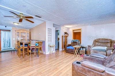 living room featuring ceiling fan, a textured ceiling, and hardwood / wood-style flooring