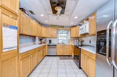 kitchen featuring stainless steel appliances, ceiling fan, and light tile patterned flooring