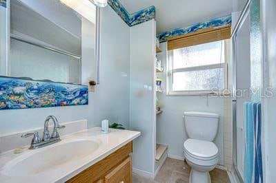 bathroom featuring walk in shower, vanity, and toilet