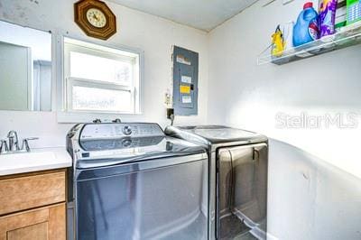 washroom featuring washing machine and clothes dryer, electric panel, and sink