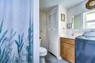 bathroom featuring toilet, vanity, and washer / dryer