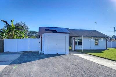 view of front of property featuring an outbuilding, a front yard, and solar panels