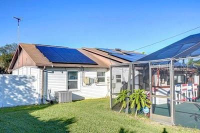 back of property featuring solar panels, a yard, and central air condition unit