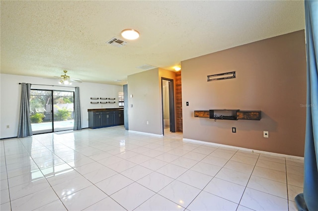 unfurnished living room with ceiling fan, light tile patterned floors, and a textured ceiling