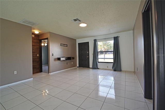 tiled empty room with ceiling fan, wood walls, and a textured ceiling