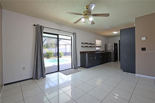 kitchen with ceiling fan, stainless steel fridge, light tile patterned floors, and a textured ceiling