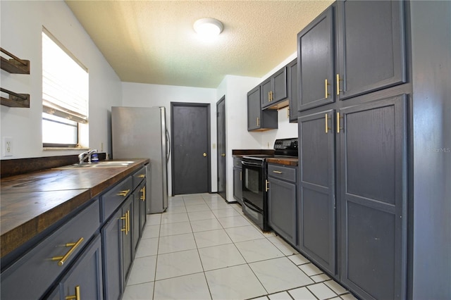 kitchen with butcher block counters, sink, black / electric stove, a textured ceiling, and light tile patterned floors