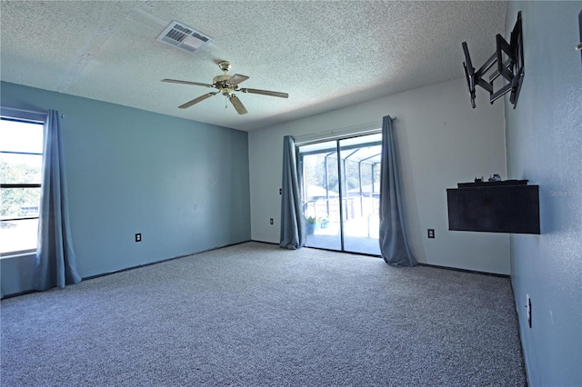 spare room featuring carpet flooring, a textured ceiling, a wealth of natural light, and ceiling fan