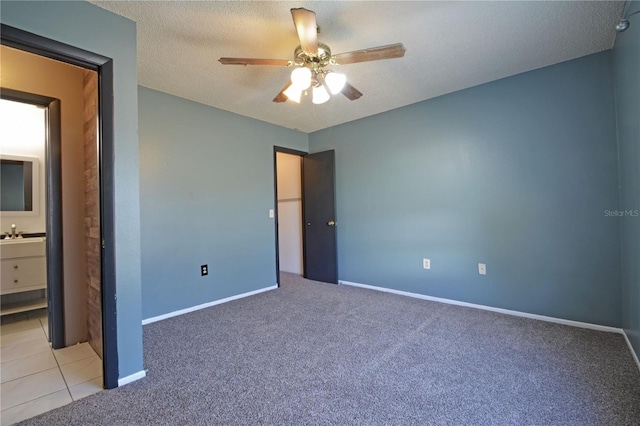 unfurnished bedroom featuring ensuite bath, ceiling fan, light carpet, and a textured ceiling