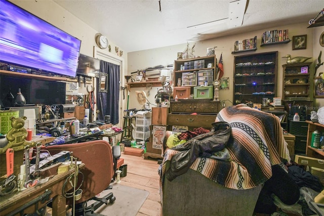 miscellaneous room with a workshop area, light wood-type flooring, and a textured ceiling