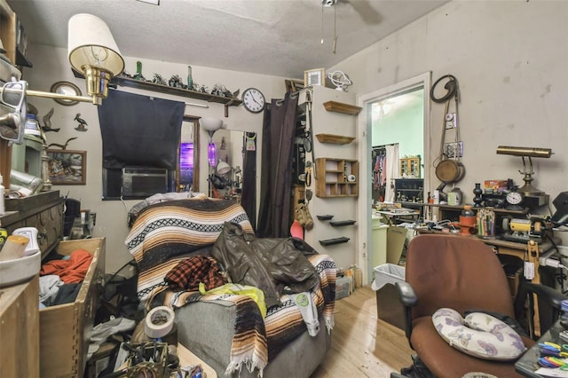 miscellaneous room featuring a textured ceiling, light hardwood / wood-style floors, ceiling fan, and cooling unit