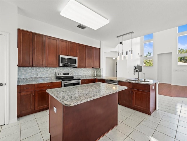 kitchen featuring sink, hanging light fixtures, kitchen peninsula, a kitchen island, and appliances with stainless steel finishes