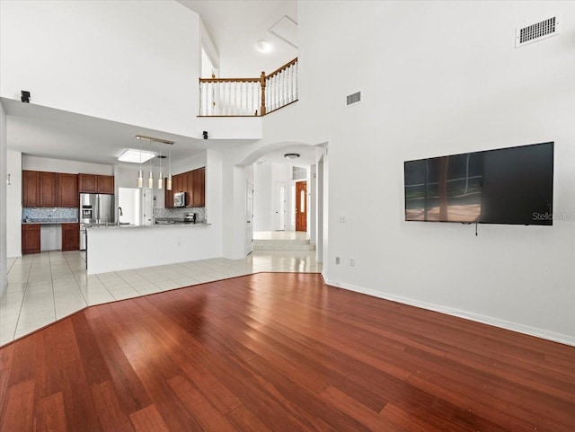 unfurnished living room featuring a high ceiling and light hardwood / wood-style floors