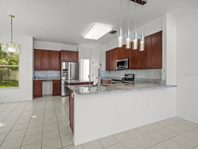 kitchen with decorative light fixtures, kitchen peninsula, appliances with stainless steel finishes, and tasteful backsplash