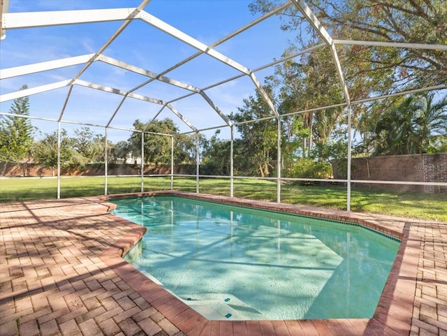 view of swimming pool featuring a yard, glass enclosure, and a patio area