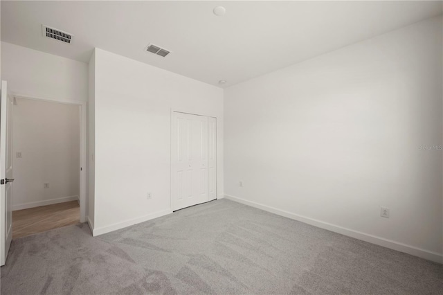 unfurnished bedroom featuring light colored carpet and a closet