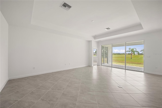 empty room featuring light tile patterned floors and a tray ceiling