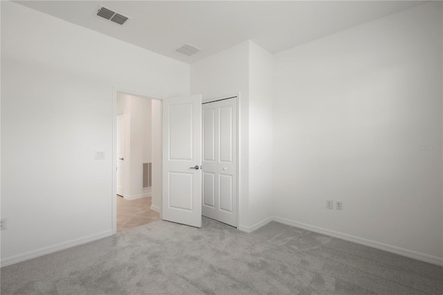 unfurnished bedroom with light colored carpet and a closet