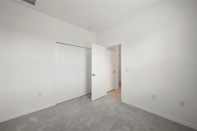 unfurnished bedroom featuring light colored carpet and a closet