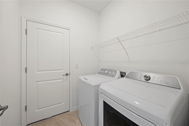 clothes washing area with independent washer and dryer and light tile patterned floors