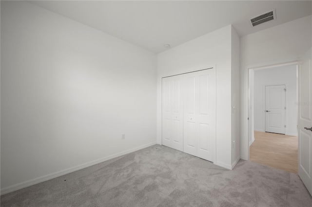 unfurnished bedroom with light colored carpet and a closet