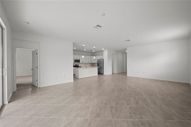 unfurnished living room featuring light tile patterned floors and sink