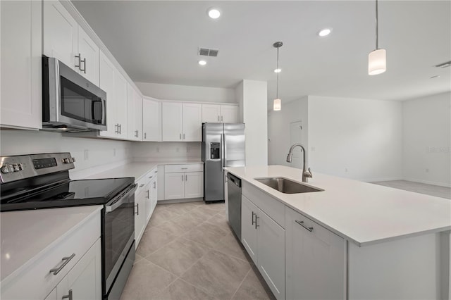 kitchen with white cabinetry, sink, hanging light fixtures, stainless steel appliances, and a center island with sink