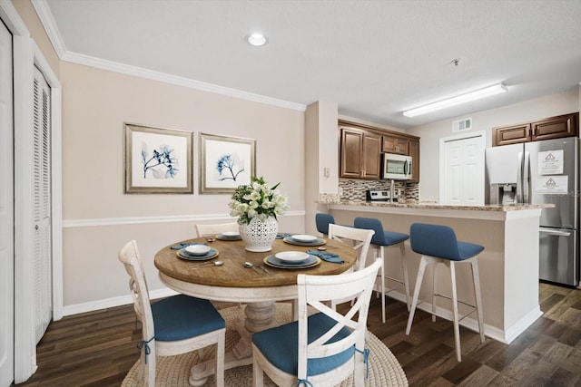 dining area with a textured ceiling, dark hardwood / wood-style floors, and crown molding