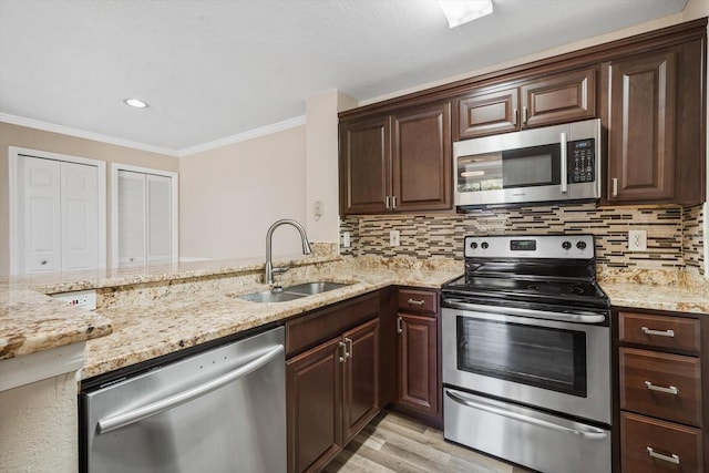 kitchen featuring sink, stainless steel appliances, light wood-type flooring, and ornamental molding