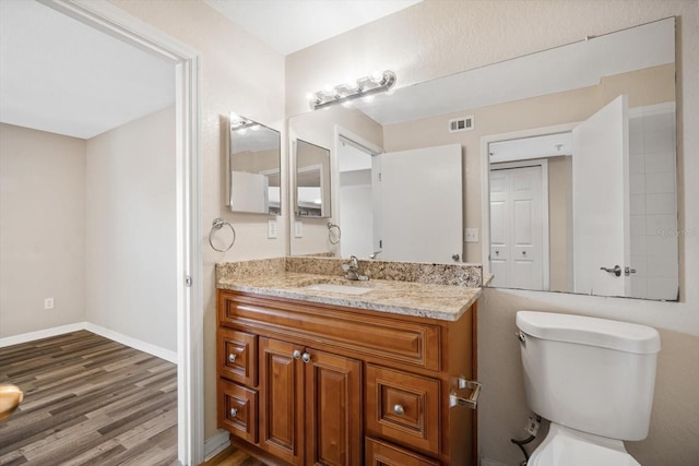 bathroom featuring vanity, wood-type flooring, and toilet